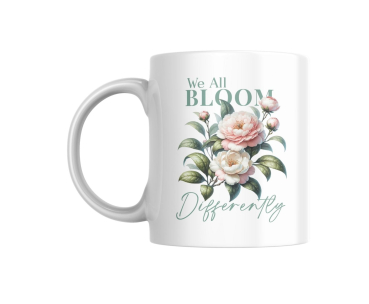 Weiße Keramiktasse mit botanischem Design und dem Zitat „We All Bloom Differently“, freigestellt auf weißem Hintergrund.